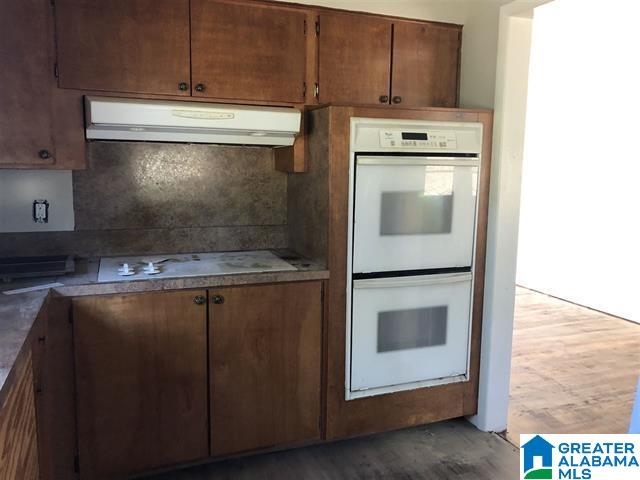 kitchen with dark wood-type flooring, white appliances, and tasteful backsplash