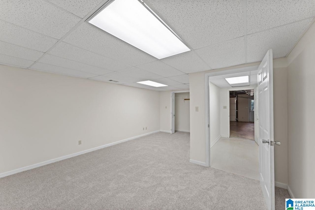 basement featuring a drop ceiling and light colored carpet