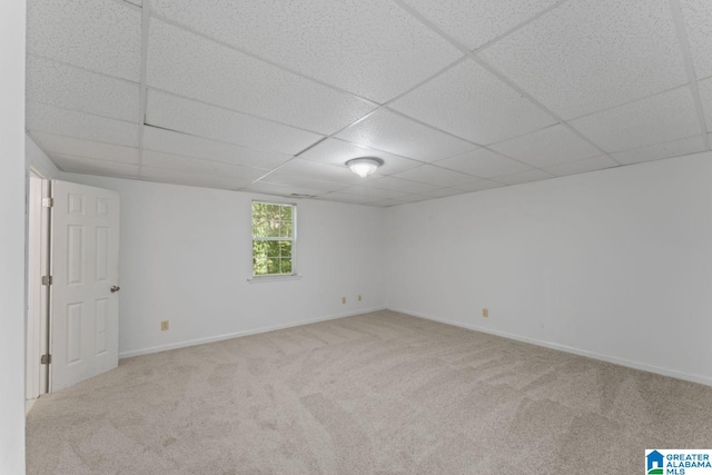 basement with a paneled ceiling and light colored carpet