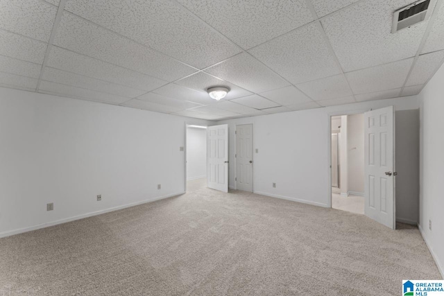 interior space with a paneled ceiling and light carpet