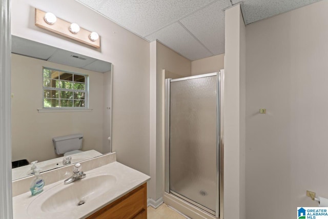 bathroom with a paneled ceiling, toilet, a shower with door, and vanity