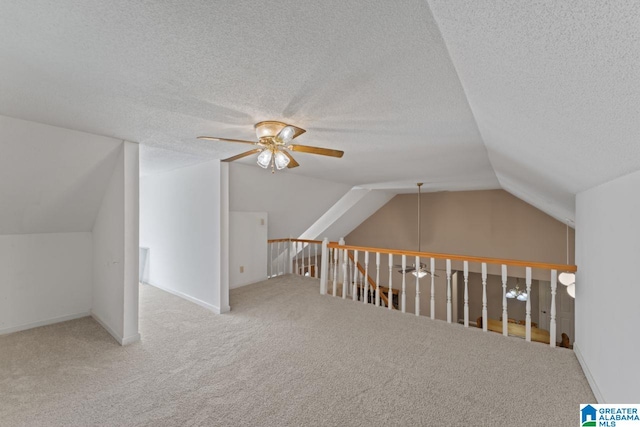 additional living space with ceiling fan, carpet flooring, a textured ceiling, and vaulted ceiling