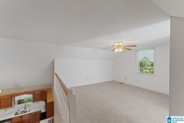 bonus room featuring light carpet, a textured ceiling, lofted ceiling, and sink