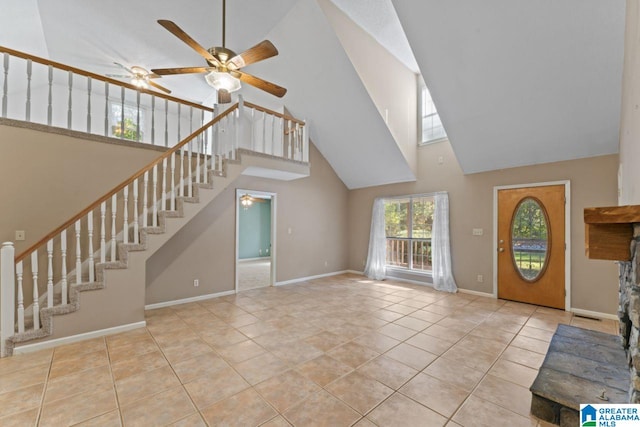 unfurnished living room featuring a high ceiling, ceiling fan, and light tile patterned floors