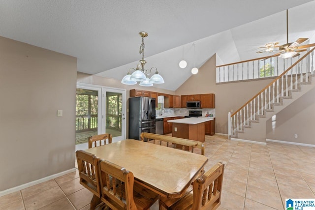 dining area featuring ceiling fan with notable chandelier, high vaulted ceiling, sink, and light tile patterned floors