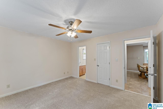 unfurnished bedroom featuring ceiling fan, a textured ceiling, a closet, and light carpet