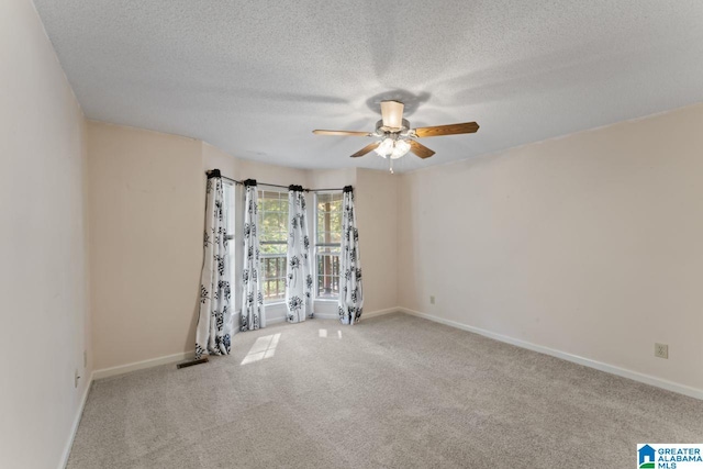 empty room with ceiling fan, a textured ceiling, and light carpet