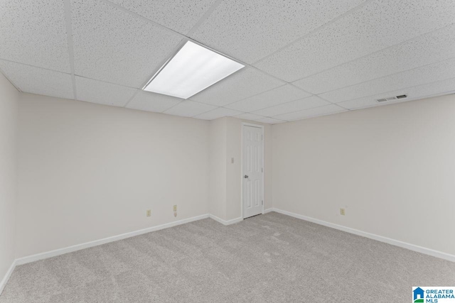 basement featuring a drop ceiling and light carpet