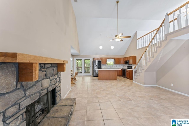 living room with light tile patterned flooring, high vaulted ceiling, ceiling fan, and a stone fireplace