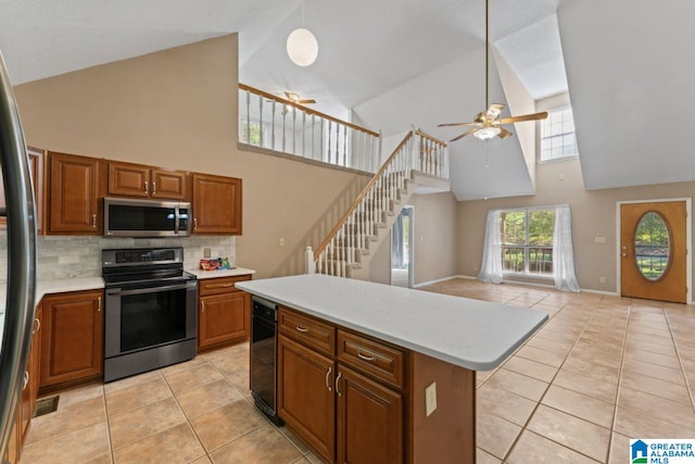 kitchen with light tile patterned flooring, stainless steel appliances, high vaulted ceiling, and a center island