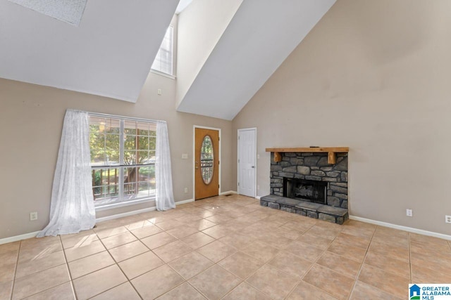 unfurnished living room with high vaulted ceiling, a stone fireplace, and light tile patterned floors