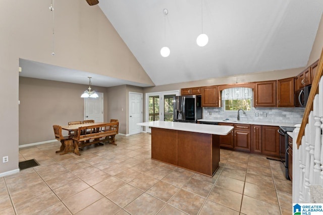 kitchen with light tile patterned flooring, a kitchen island, decorative light fixtures, stainless steel appliances, and high vaulted ceiling