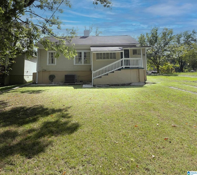 rear view of property featuring cooling unit and a lawn