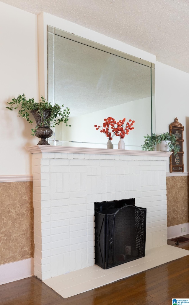 interior details with a brick fireplace, hardwood / wood-style floors, and a textured ceiling