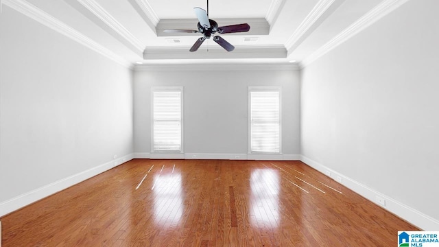 empty room with ornamental molding, a tray ceiling, hardwood / wood-style flooring, and ceiling fan