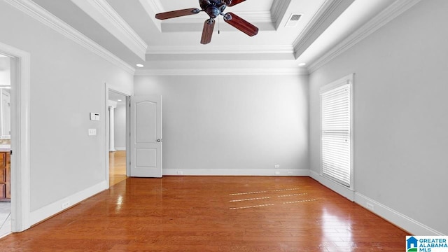 spare room with a raised ceiling, ornamental molding, hardwood / wood-style flooring, and ceiling fan