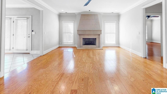 unfurnished living room featuring ceiling fan, light wood-type flooring, crown molding, and a tile fireplace