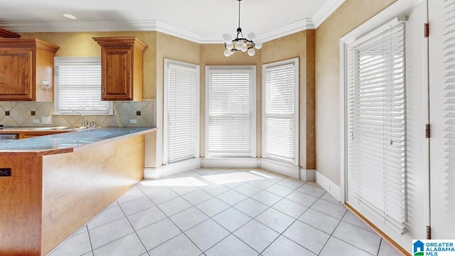 kitchen featuring light tile patterned flooring, tasteful backsplash, decorative light fixtures, a notable chandelier, and crown molding