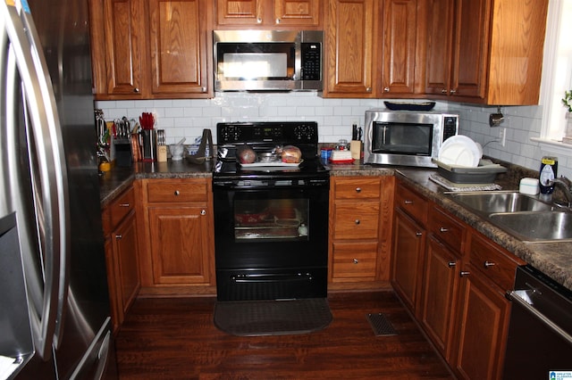 kitchen with dark wood-type flooring, backsplash, appliances with stainless steel finishes, and sink