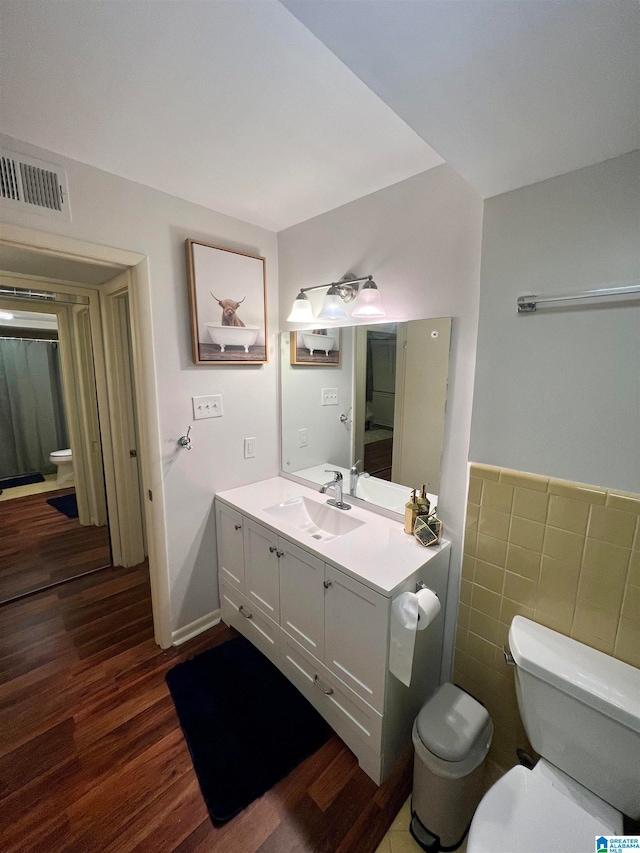 bathroom featuring vanity, toilet, hardwood / wood-style flooring, and tile walls