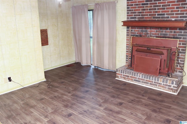 unfurnished living room featuring a brick fireplace and dark wood-type flooring