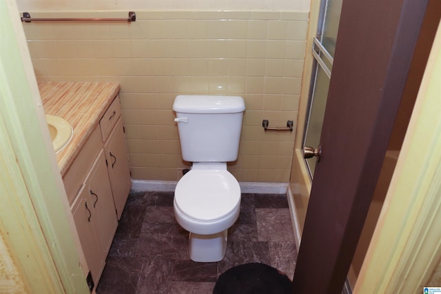 full bathroom featuring tile walls, toilet, vanity, and combined bath / shower with glass door