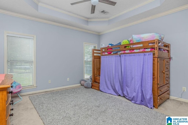 carpeted bedroom with ceiling fan, a tray ceiling, and ornamental molding