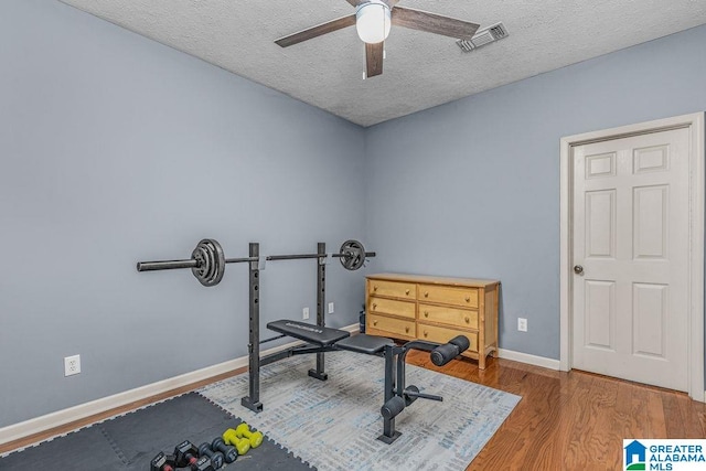 exercise room featuring ceiling fan, hardwood / wood-style floors, and a textured ceiling