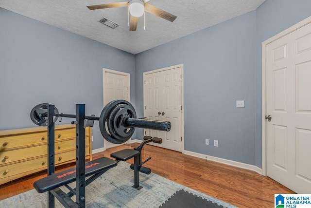 workout area featuring ceiling fan, hardwood / wood-style floors, and a textured ceiling