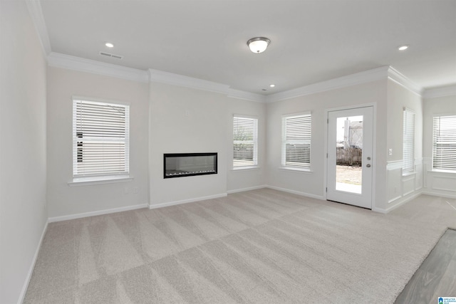 unfurnished living room with crown molding, plenty of natural light, and light colored carpet