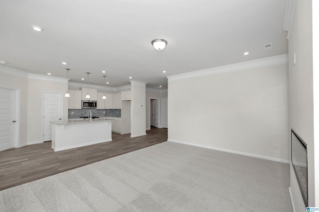 unfurnished living room with sink, crown molding, and hardwood / wood-style flooring