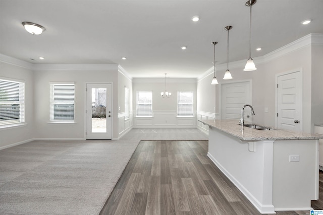 kitchen featuring dark wood-type flooring, sink, decorative light fixtures, light stone countertops, and a kitchen island with sink