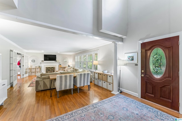 entryway featuring ornate columns, ornamental molding, and light hardwood / wood-style floors