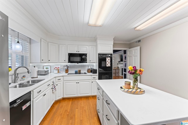 kitchen featuring hanging light fixtures, sink, white cabinetry, black appliances, and light wood-type flooring