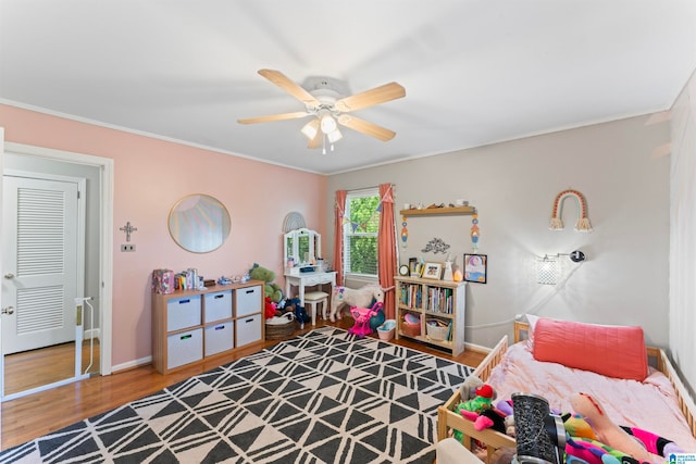 bedroom featuring ceiling fan, ornamental molding, a closet, and hardwood / wood-style floors