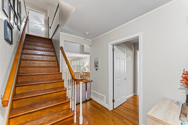 stairway featuring hardwood / wood-style flooring and crown molding