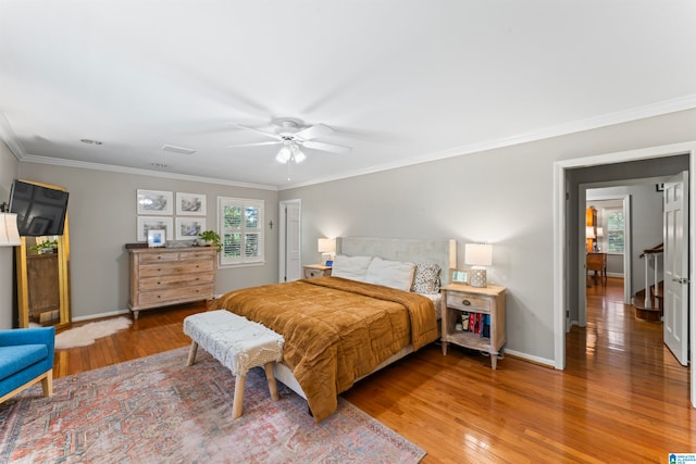 bedroom with multiple windows, ceiling fan, wood-type flooring, and crown molding