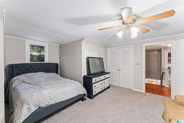 bedroom featuring ceiling fan, light colored carpet, a closet, and ornamental molding