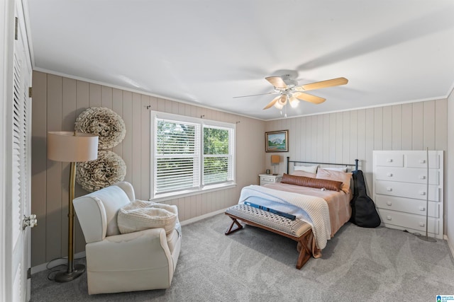 bedroom with ceiling fan, light carpet, wood walls, and crown molding