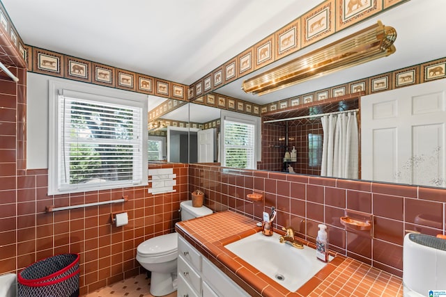 bathroom with walk in shower, tile walls, vanity, and toilet