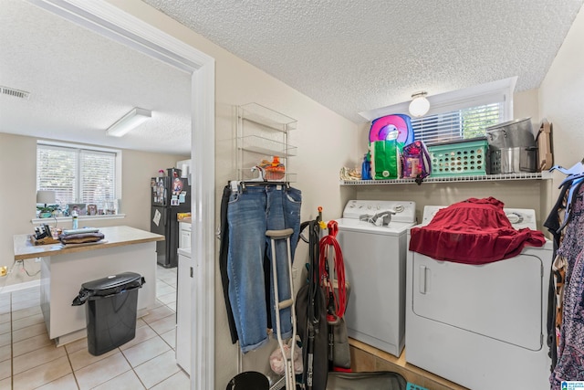 laundry area featuring independent washer and dryer, light tile patterned floors, and a textured ceiling