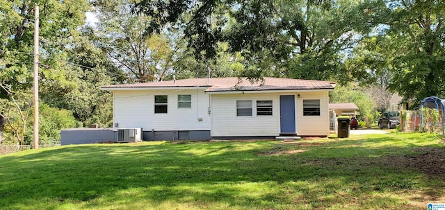 rear view of house with cooling unit and a lawn