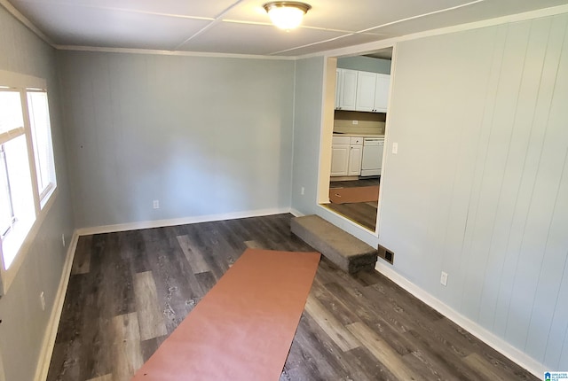 unfurnished room featuring crown molding, wooden walls, and dark hardwood / wood-style floors