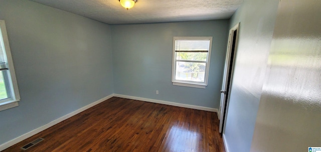 spare room featuring dark hardwood / wood-style floors and a textured ceiling