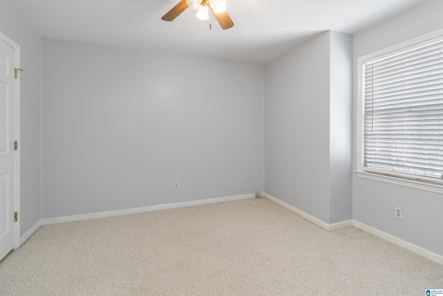 empty room with light colored carpet, a wealth of natural light, and ceiling fan