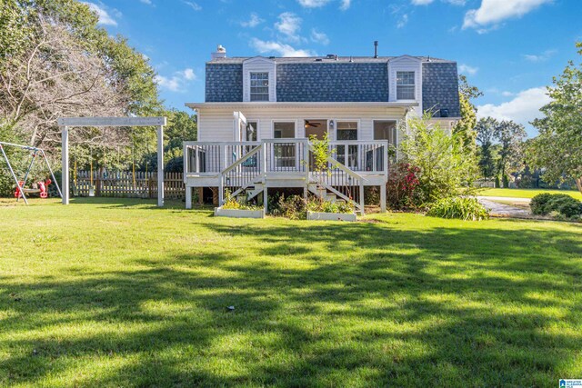 back of house featuring a playground, a yard, and a wooden deck