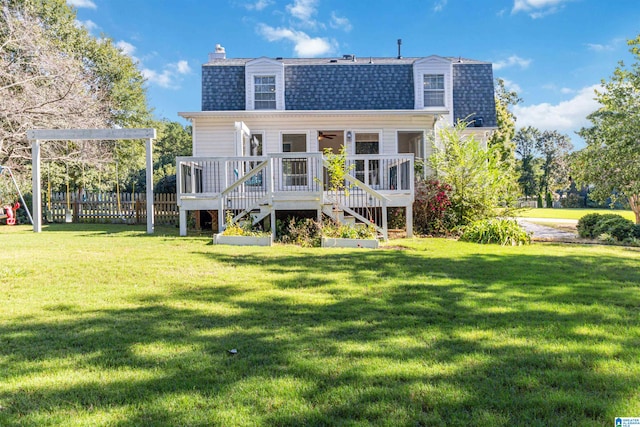 rear view of house featuring a lawn and a deck