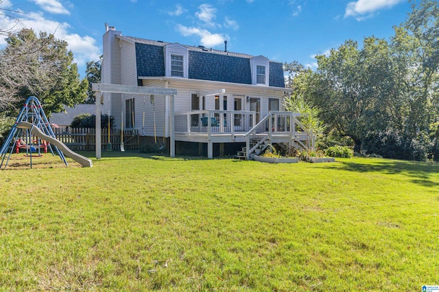 rear view of house featuring a playground, a wooden deck, and a lawn