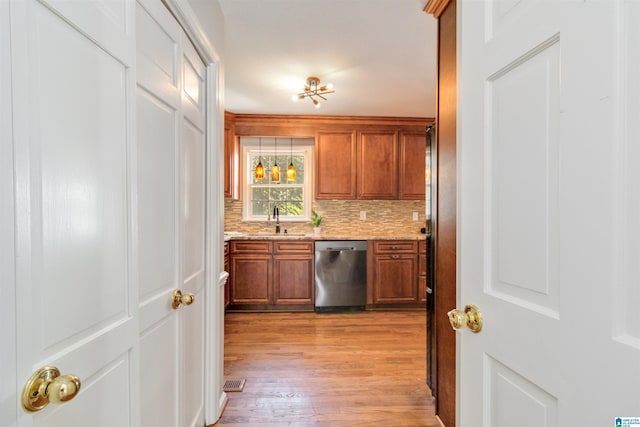 kitchen with decorative backsplash, light hardwood / wood-style flooring, sink, dishwasher, and light stone countertops