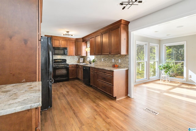 kitchen featuring sink, light hardwood / wood-style flooring, black appliances, light stone countertops, and crown molding